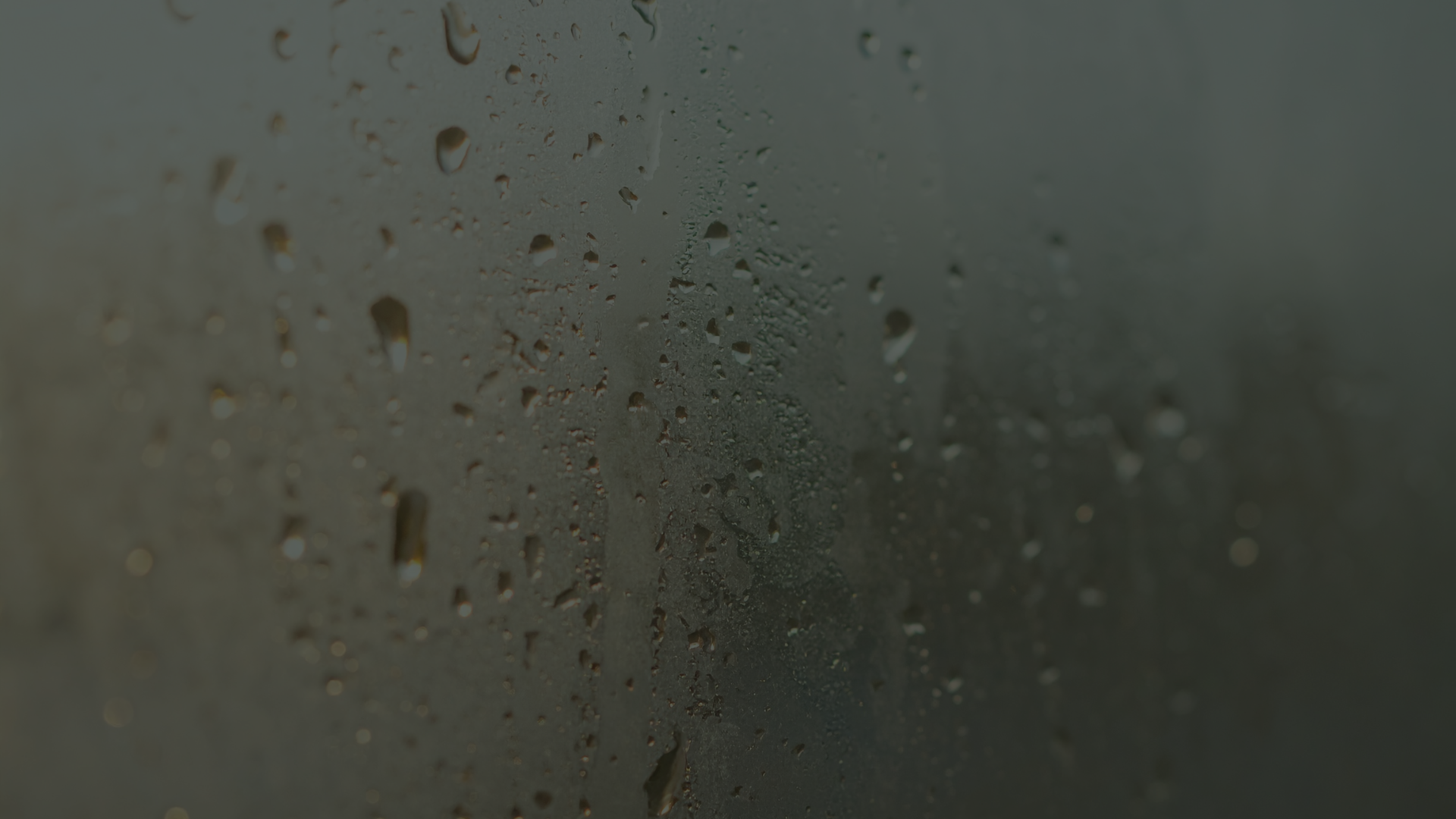 Close-up of water droplets and heavy condensation on a foggy glass window.